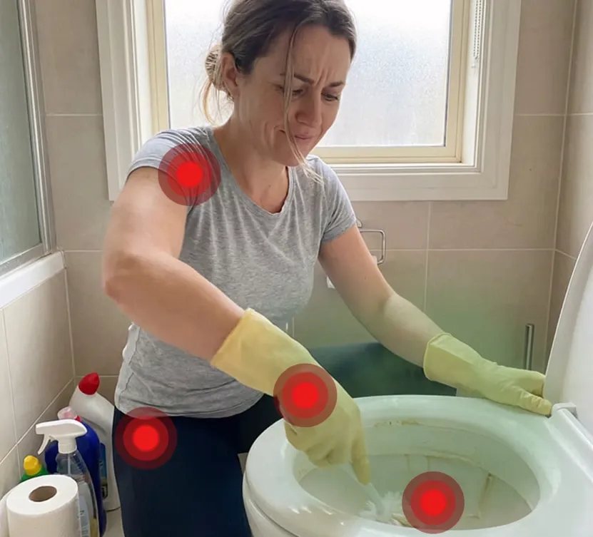 Frau kniet mit Gummihandschuhen vor der Toilette und schrubbt